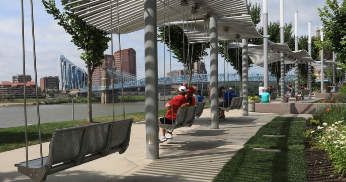 People sit on swinging benches along the river in Cincinnati, OH